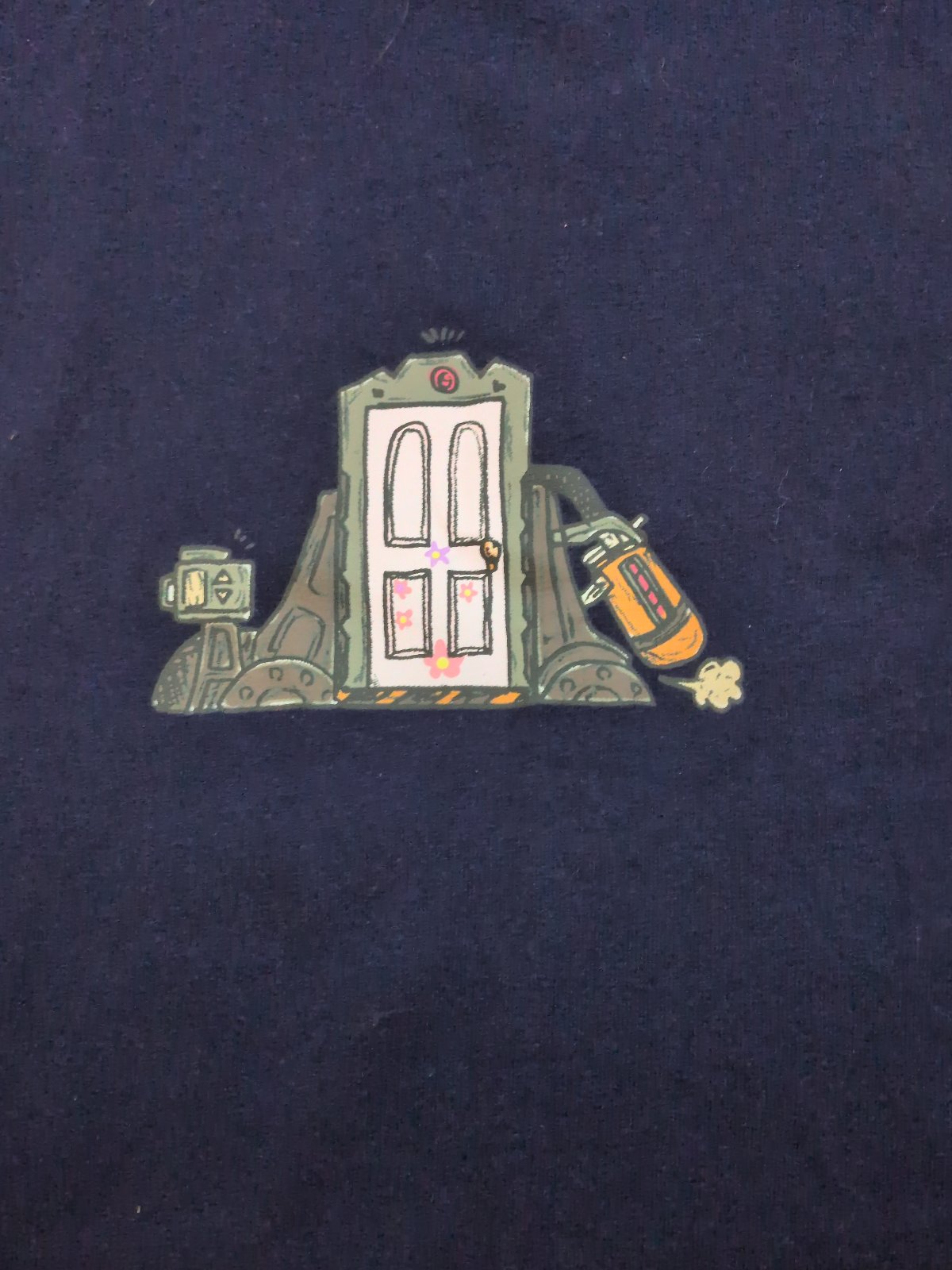 Navy blue short-sleeved t-shirt with a small printed monster-factory door on the chest and, on the reverse, the arched text "SULLEY&MIKE / WE SCARE BECAUSE WE CARE" above cartoon blue and green monsters.